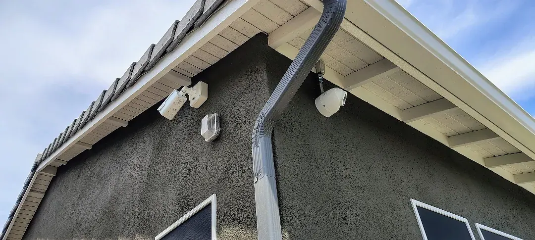 Exterior security camera installations beneath the roofline of the Surprise home